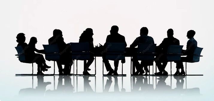 Silhouettes of people seated around a meeting table.