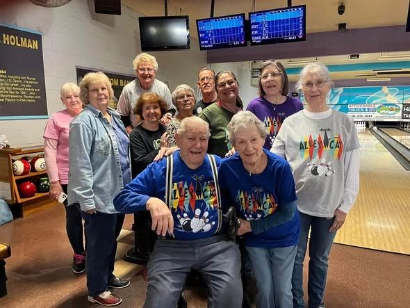 Group of seniors posing happily at a bowling alley.