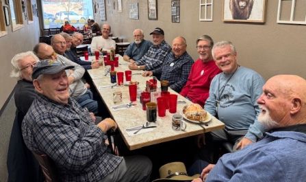 Group of men enjoying a meal together at a long table.
