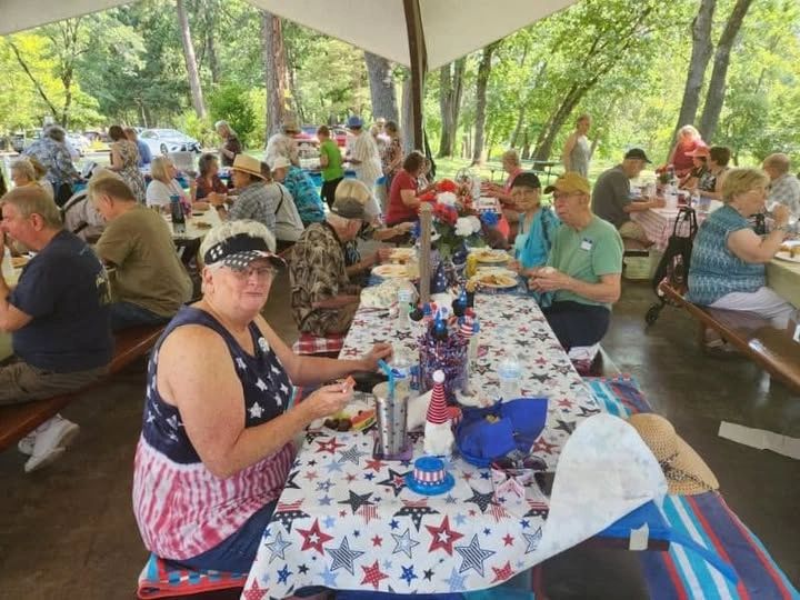 People enjoying a patriotic picnic under a pavilion.